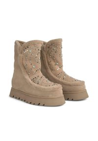 Beige Wildlederstiefel mit Fellfutter, verziert mit dekorativen Strasssteinen und einer Wedge-Sohle mit einem robusten Profil.