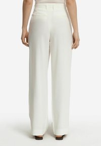 Pantaloni bianchi a gamba larga con una texture liscia e una vita elastica, dotati di due tasche posteriori e un design pulito e minimalista.