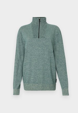 Pikendega kootud pullover, millel on tekstureeritud roheline kangas ja veerandist tõmblukk kõrges kraes, esitatud lihtsal taustal.