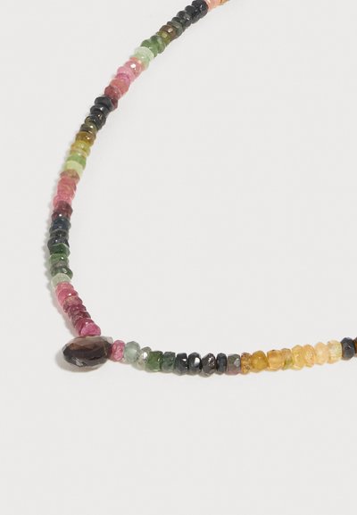 Perles de pierres précieuses multicolores facettées enfilées ensemble, formant un collier partiellement circulaire sur un fond blanc uni.