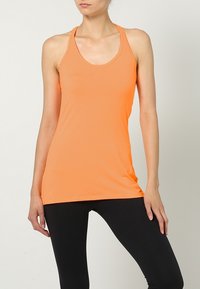 Top atletico arancione brillante con scollatura tondeggiante e spalline sottili, abbinato a leggings neri, realizzati in tessuto elastico e traspirante.