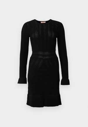 Crna pletena haljina dugih rukava, s rebrastom teksturom, uskim strukom i raširenim rubom. Ima okrugli izrez i suptilne dizajnerske detalje.
