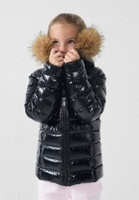 Zwarte donsjack met een glanzende afwerking, voorzien van een ritssluiting aan de voorkant en bont pompons op de capuchon. Licht doorgestikte delen zichtbaar.