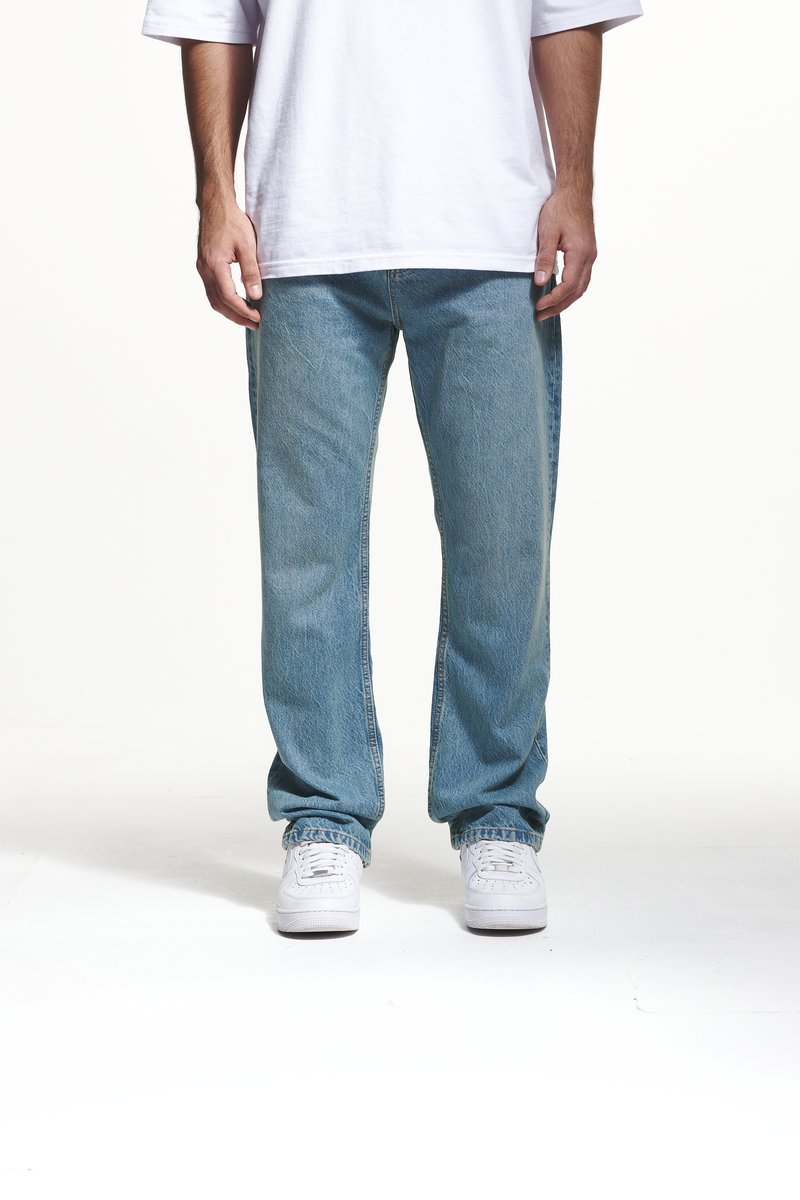 Lichtblauwe spijkerbroek met een relaxte pasvorm, recht pootontwerp en subtiele textuurdetails, gecombineerd met witte sneakers.