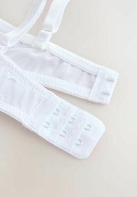 Bretelele albe ale sutienului sunt căptușite cu plasă moale și au clipsuri ajustabile. Închiderea din spate are mai multe opțiuni de cârlige și ochi pentru o potrivire perfectă. Textura este netedă pe întreaga suprafață.