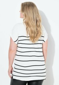 Camiseta blanca con rayas horizontales negras, de mangas cortas y un corte relajado. La tela parece suave con una textura lisa.