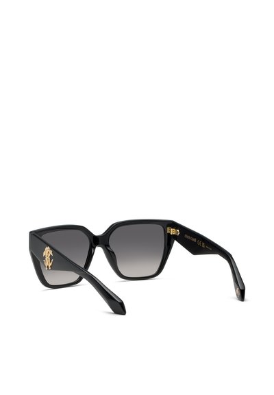 Lunettes de soleil noires forme œil de chat avec verres foncés dégradés et détails d'emblèmes dorés sur les branches sur fond blanc.