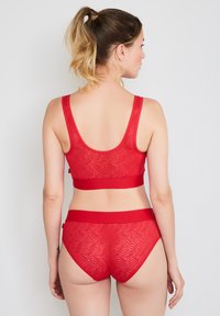 Red lingerie set featuring a ribbed bralette and high-waisted brief with a wave pattern. Soft, stretchy fabric and wide elastic bands.