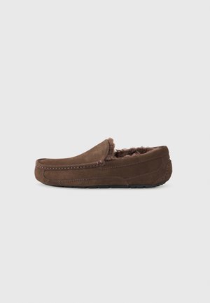 Pantofole in camoscio marrone con una morbida imbottitura interna in pelliccia, design a profilo basso e dettagli di cucitura lungo i bordi. Nessun marchio o accento visibile.