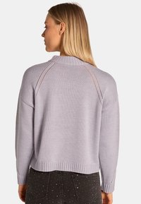Maglione lavanda chiaro con colletto e orlo a coste, caratterizzato da dettagli a maglia aperta sulle spalle e una vestibilità rilassata.