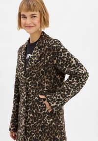 Een leoprint jas van zachte stof met een klassiek ontwerp, notch-revers, enkele knoopsluiting en zijzakken.