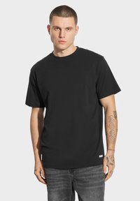 Czarna bawełniana koszulka z okrągłym dekoltem i krótkimi rękawami, z minimalistycznym wzorem i małym białym logo na dolnym końcu.