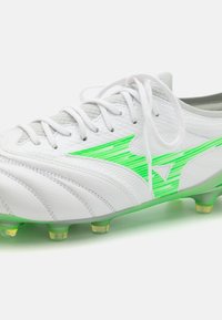 Witte voetbalschoenen met een textuur, groene gestreepte accenten en een transparante zool met gele studs. Inclusief grijze veters.