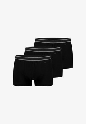 Tre sorte herreboxershorts med grå elastiske taljebånd arrangeret i en forskudt række på en hvid baggrund.