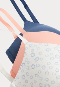 Trois bralettes en bleu marine, rose clair et blanc avec un motif floral bleu ; en coton ; bretelles réglables ; texture lisse.
