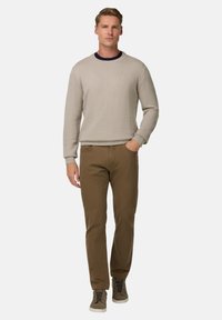 Sweater en maille petit beige clair avec un col rond, associé à un pantalon marron et des baskets montantes grises. Design simple, sans motifs visibles.