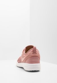 Nike buty sportowe w jasnoróżowym kolorze z teksturowaną siateczką, amortyzowaną podeszwą i pętelką na pięcie ułatwiającą zakładanie. Gładka biała podeszwa.