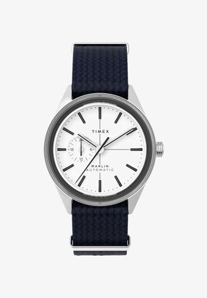 Die Timex Marlin automatische Uhr verfügt über ein weißes Zifferblatt mit schwarzen Stundenmarkierungen, ein Stahlgehäuse und ein dunkelblaues gewebtes Stoffarmband.