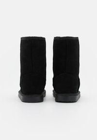 Black suede ankle boots with a soft texture, flat rubber soles, and a slight heel. Features a rounded toe and minimal stitching accents.