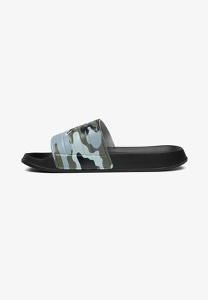 Sandale slide noire avec une large sangle à motif camouflage sur le pied, présentant des nuances de vert, gris et bleu.