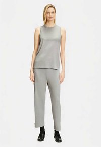 Graues ärmelloses Oberteil mit rundem Ausschnitt und passende graue Hose. Der Stoff wirkt glatt, und das Design ist minimalistisch und maßgeschneidert.