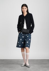Črna rebrasta cardigan, bela majica, jeans kratke hlače s cvetličnim vezenjem, prozorne bele nogavice, črna prešita torba, srebrni špičasti balerinki.