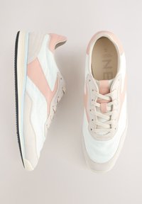 Sneakers med en hvid og beige overdel, rosa accenter og tekstureret ruskind. Har snørelukning og en sort gummisål.