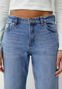 Ljust blå denimjeans med hög midja, med knapplås och dragkedja, diskret blekning och klassisk femficksdesign.