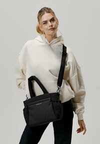 Bolso de hombro acolchado negro con asas dobles y correa ajustable. Material suave con ligero brillo, con logotipo en la parte frontal.