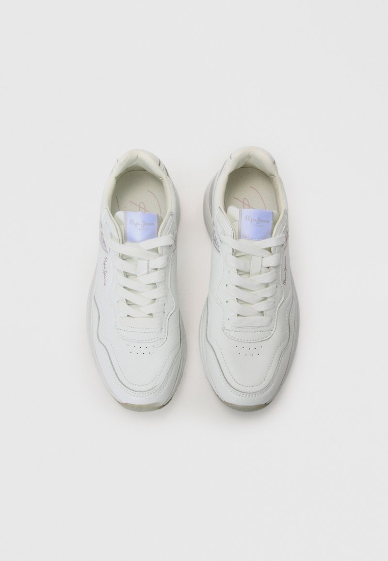 Un par de zapatillas blancas con cordones y parches de logo color púrpura claro en las lengüetas, con detalles de costura sutiles, colocadas sobre un fondo blanco.