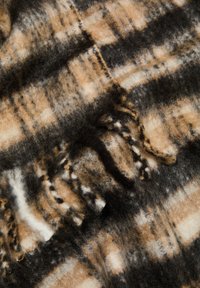 Couverture en laine avec un motif à carreaux brun, noir et crème, dotée d'une surface douce et texturée et de finitions à franges sur les bords.