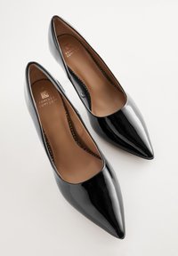 Décolleté nere in vernice con tacco alto e punta appuntita. Interno con soletta in pelle marrone con rilievo "Forever Comfort".