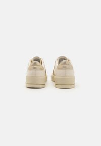 Sneaker Skechers beige con tomaia in pelle liscia, colletto imbottito e suole in gomma spesse. Logo impresso sul tallone.