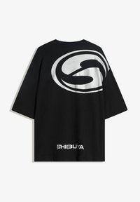 Musta lyhythihainen t-paita, jossa on suuri metallinhohtoinen hopea logo selässä ja "SHIBUYA NIGHTS" -teksti lähellä alahelmaa.