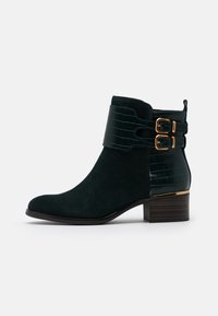 Botines de ante verde oscuro con un panel de cuero de estampado de cocodrilo, hebillas doradas y un tacón de bloque de madera.