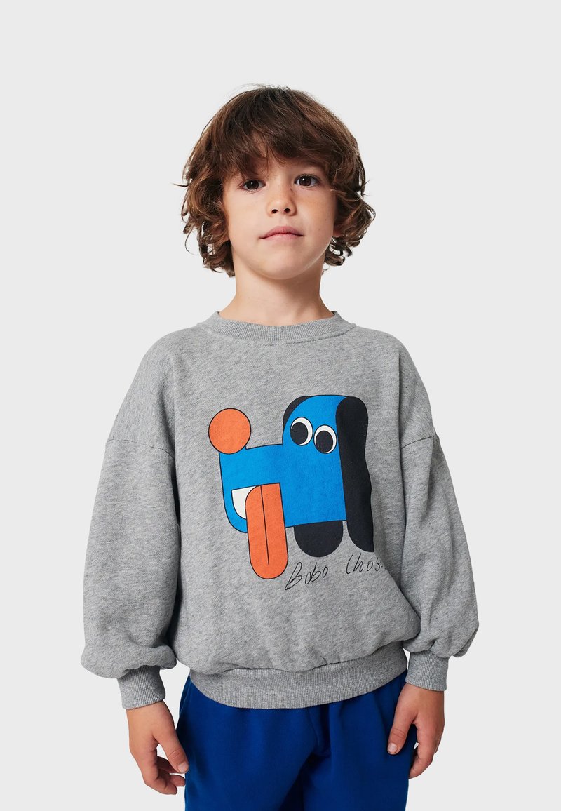 Felpa grigia con un design grafico colorato che presenta elementi blu, arancioni e neri. Tessuto morbido, vestibilità rilassata, polsi a costine.
