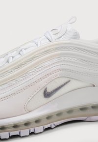Primo piano di una sneaker Nike Air Max bianca che mostra dettagli in mesh, pelle, cuciture, lacci, linguetta e suola con ammortizzazione visibile.