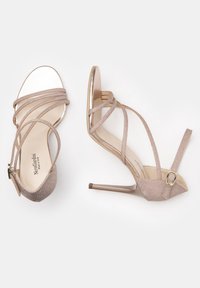 Hochhackige Sandalen mit Riemchen aus schimmerndem, hellbeigem Material. Mit zarten Riemen, offener Zehenpartie und einem metallischen Schnallen-Detail.