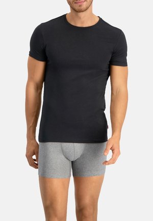 Schwarzes, eng anliegendes T-Shirt aus glattem Stoff mit kurzen Ärmeln, kombiniert mit grauen Boxershorts, die eine enganliegende Passform und ein minimalistisches Design zeigen.