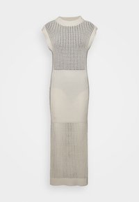Gebreide jurk in crème met een aansluitende pasvorm. Heeft een geribbelde textuur en een open mesh-patroon aan de bovenkant. Mouwloos met een hoge halslijn.