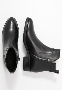 Botines de cuero negro con un acabado suave, tacón apilado, cremallera lateral y paneles elásticos laterales para un uso fácil.