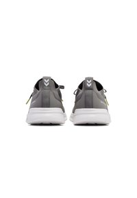 Grijze sport schoenen met witte zolen, textuurstof en contrasterende gele accenten. Bevat een trekband en reflecterende details op de hak.