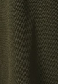 Khaki prążkowana tkanina o teksturowanym wykończeniu, z delikatnymi poziomymi liniami. Kolor to stonowany odcień ziemi.