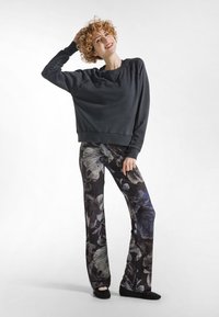 Felpa grigio scuro con maniche lunghe e orlo a costine, abbinata a pantaloni a gamba larga con motivo floreale in nero, bianco e blu.