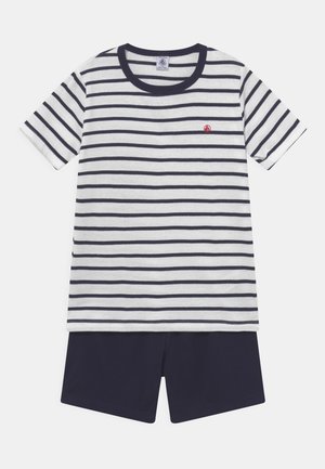 Raidallinen puuvillapaita, jossa on tummansininen trimmi ja pieni punainen logo, yhdistettynä yksivärisiin tummansinisiin shortseihin. Mukavaa vapaa-ajan vaatetusta lapsille.