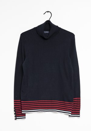 Pull à col roulé bleu marine avec des rayures horizontales rouges et blanches sur les poignets et l'ourlet, suspendu à un cintre noir sur un fond blanc.