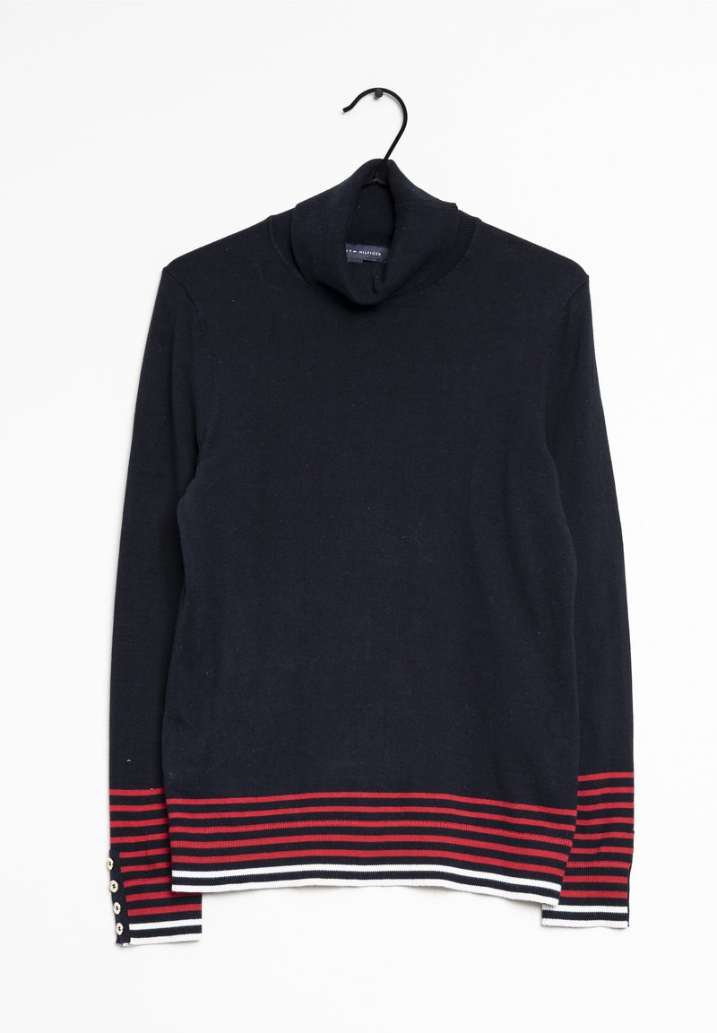 Pull à col roulé bleu marine avec des rayures horizontales rouges et blanches sur les poignets et l'ourlet, suspendu à un cintre noir sur un fond blanc.