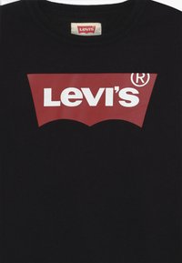 Svart bomullssweatshirt med en stor rød Levi's-logo med hvit tekst, plassert sentralt innenfor en karakteristisk rød flaggermusgrafikk.