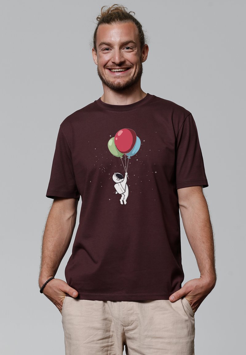 Bordeauxrood T-shirt met een afbeelding van een astronaut die kleurrijke ballonnetjes vasthoudt. Gemaakt van katoen, met een ontspannen pasvorm en korte mouwen.