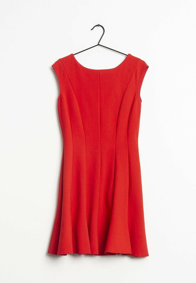 Robe rouge sans manches avec un corsage ajusté et une jupe évasée suspendue sur un cintre noir contre un fond blanc.